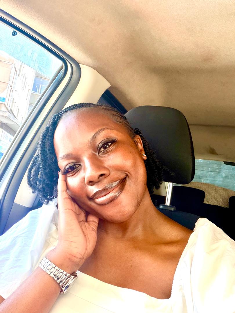 Natalie smiling softly in the car, head resting on her hand